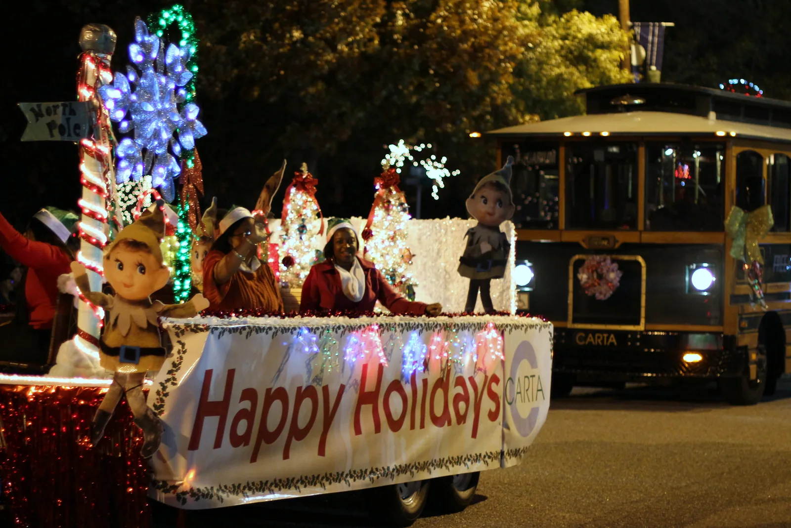 A lighted Happy Holidays float in a nighttime Christmas parade in North Charleston, South Carolina