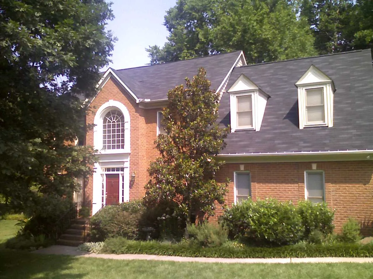 A two-story brick house with dormer windows in a Huntersville neighborhood