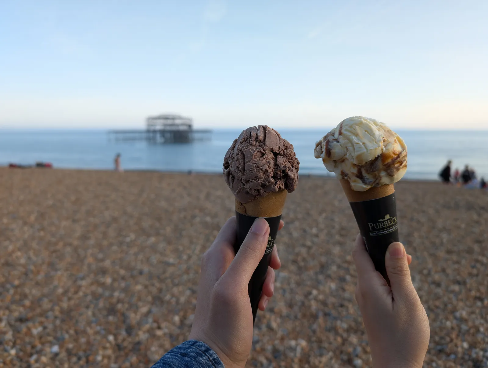 Two ice cream cones on a beach in Brighton, England; the photo does not show a Huntersville shop.