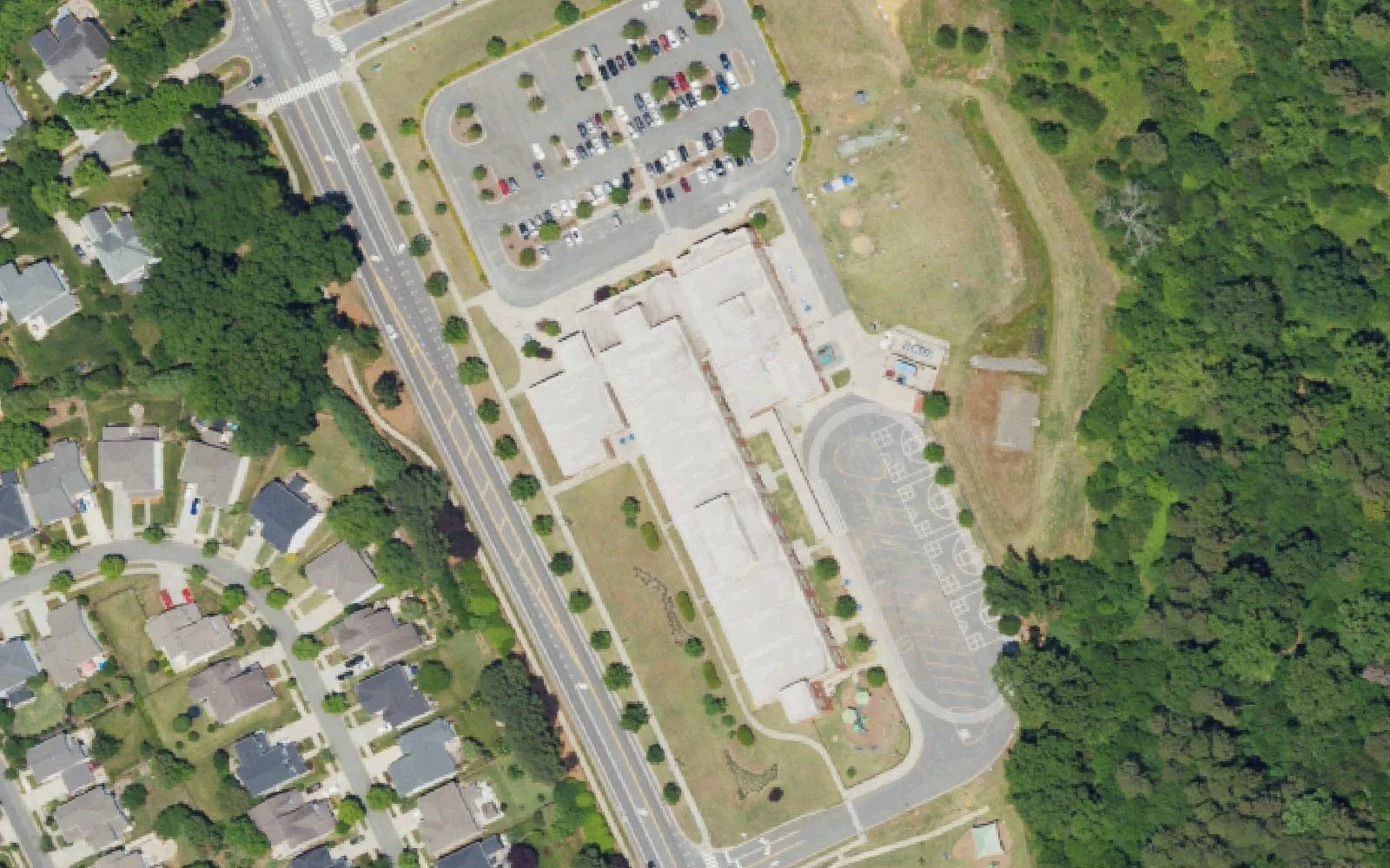 Grand Oak Elementary School and its parking lot beside Stumptown Road in Huntersville, with homes across the road, seen from the air