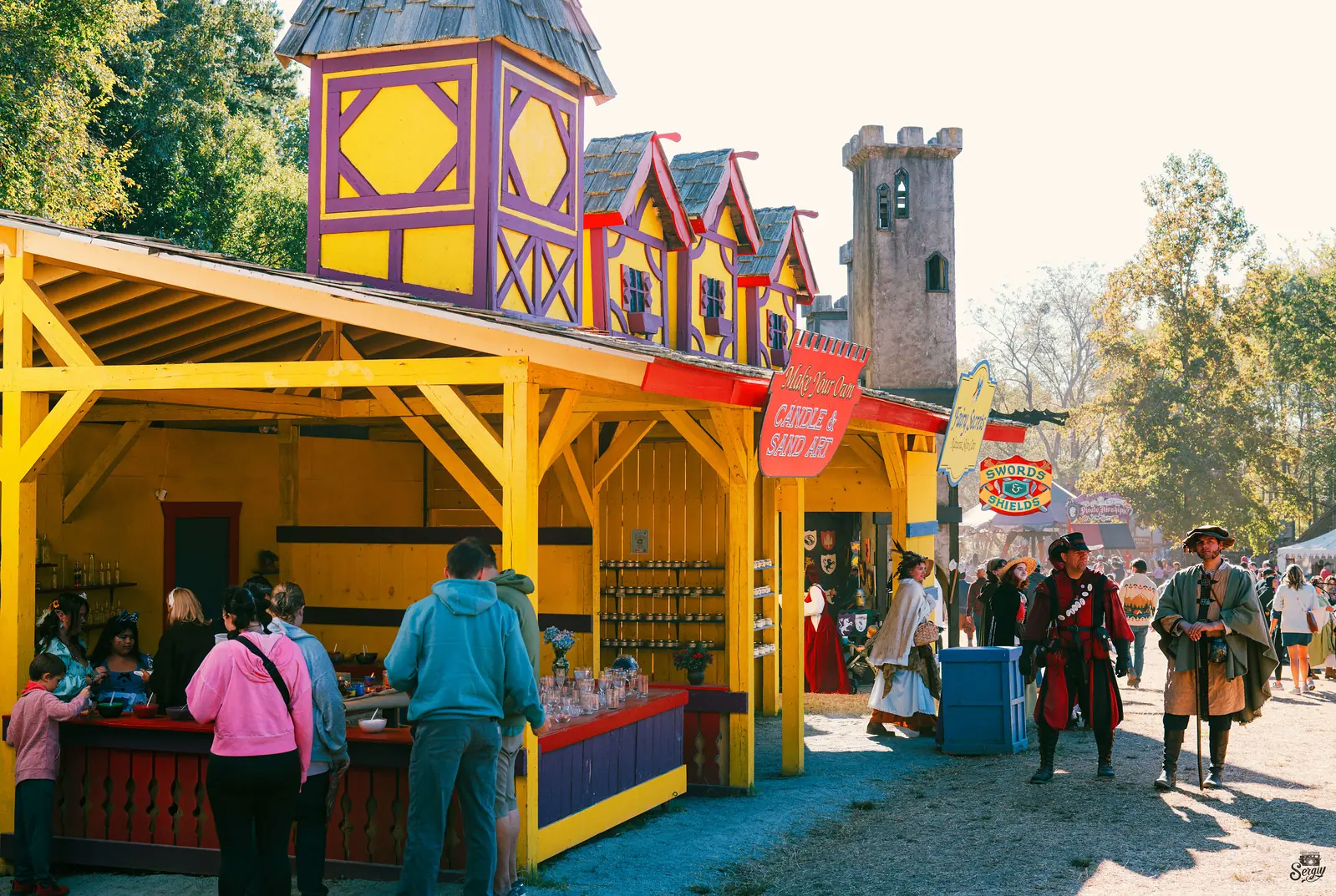 Visitors among the painted shop fronts of the Carolina Renaissance Festival village in Huntersville
