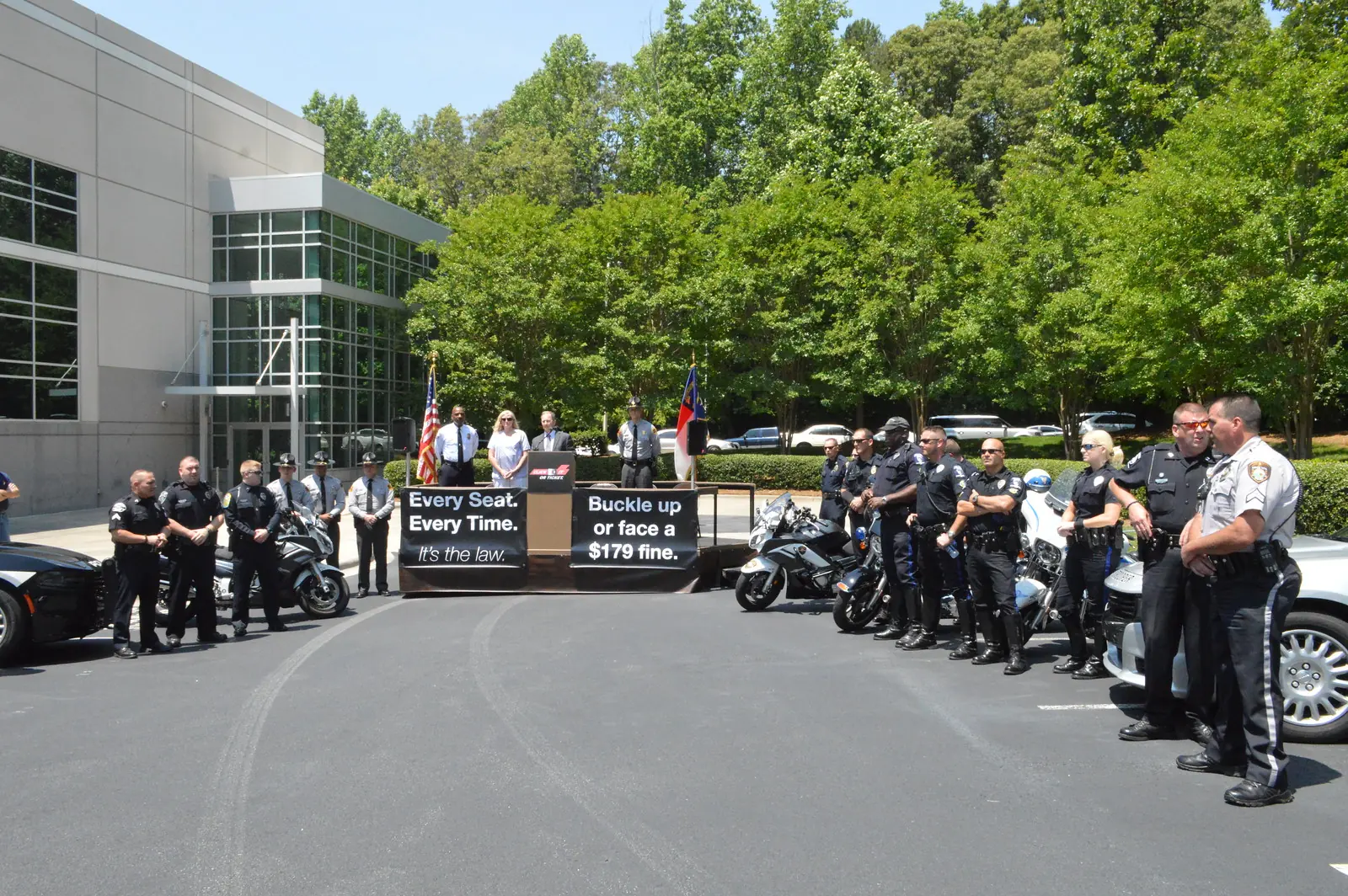 Huntersville police officers and state troopers line up beside their cars and motorcycles at a seat belt safety event in Huntersville